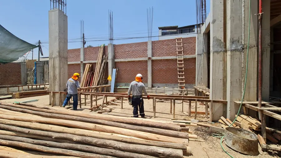 Maestros de obra armando encofrado de vigas en una construcción en Lima